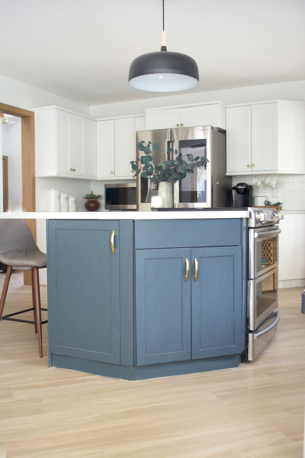 Painted blue kitchen island with wood look tile floors surrounding